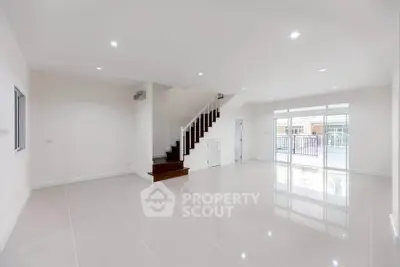 Spacious modern living room with glossy tile flooring and staircase