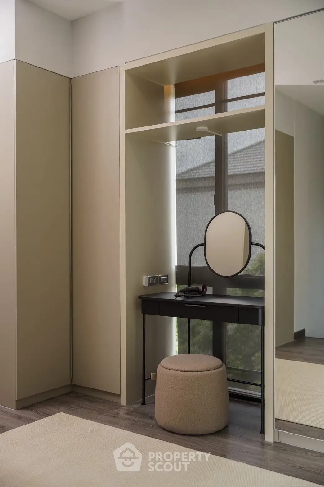 Modern bedroom corner with stylish vanity and mirror, featuring sleek design and natural light.