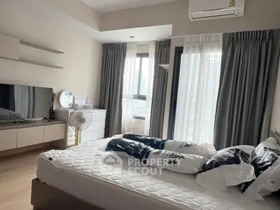 Modern bedroom with large windows and city view, featuring stylish decor and ample natural light.