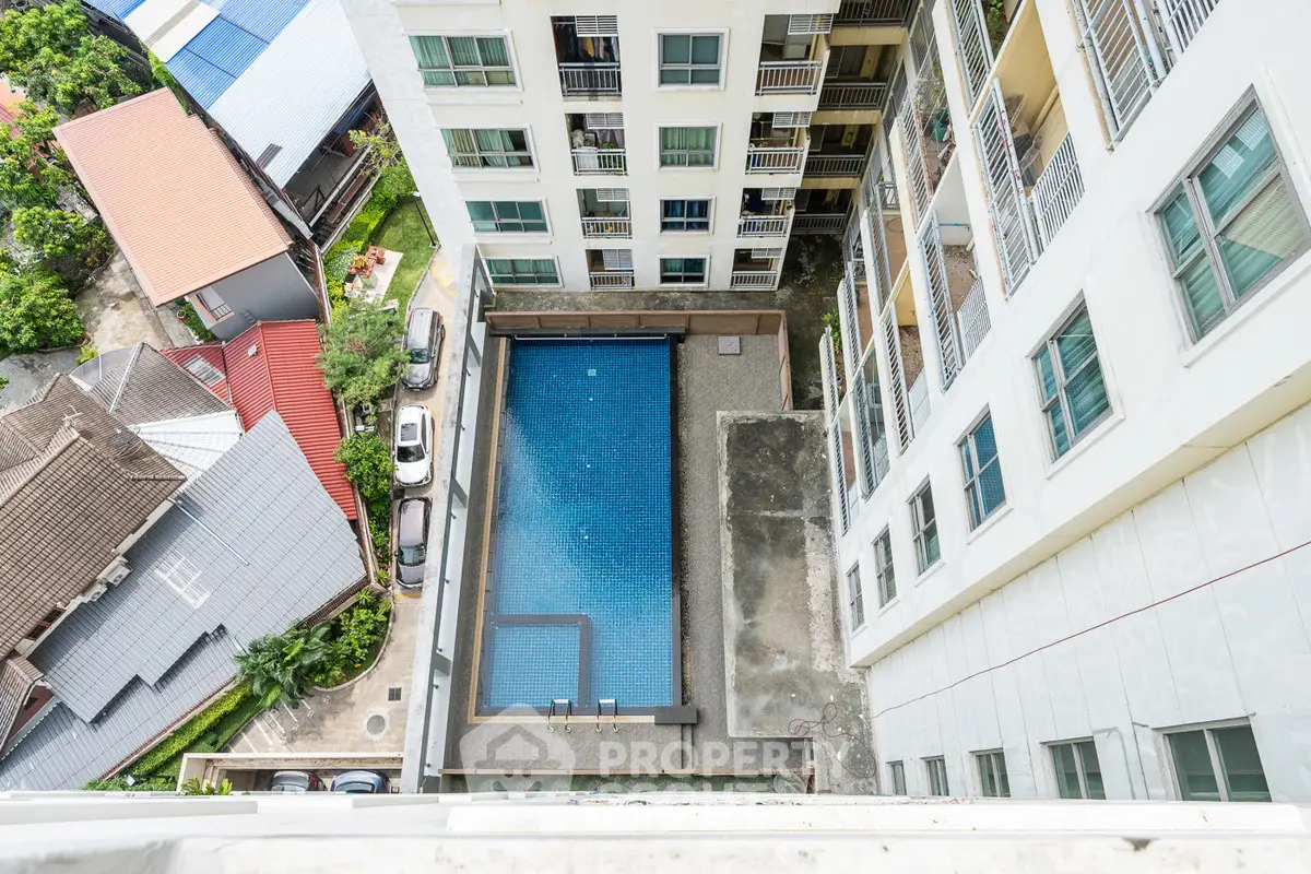 Stunning aerial view of modern apartment building with inviting swimming pool and surrounding neighborhood.