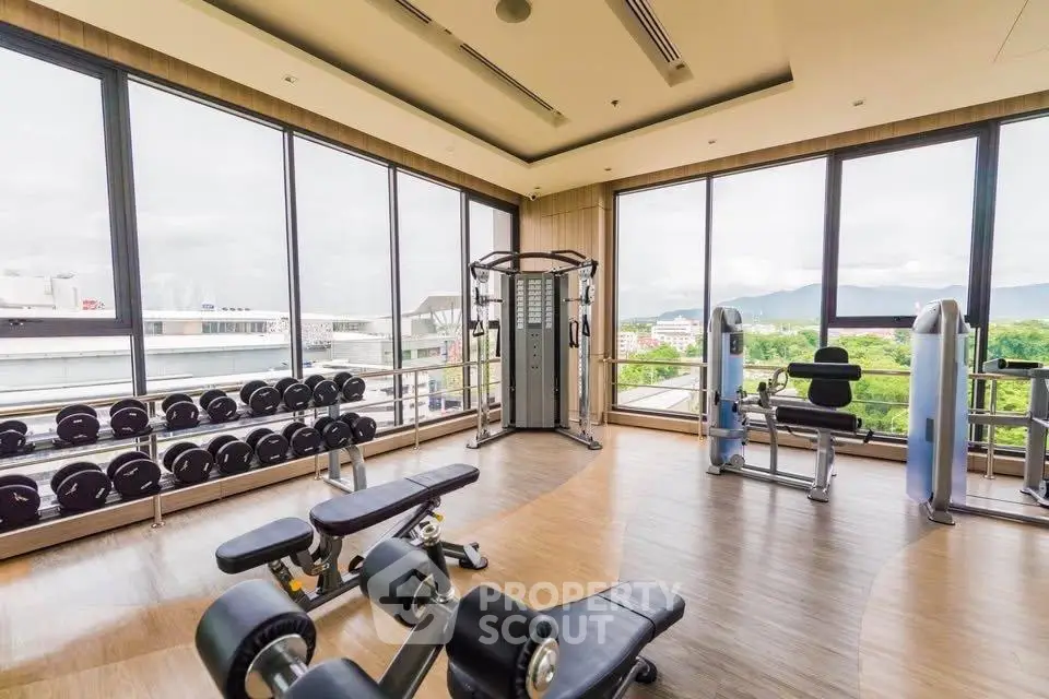 Spacious gym with modern equipment and panoramic views in luxury building.