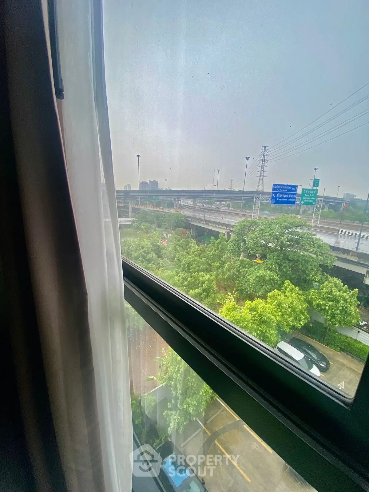 Scenic view from window overlooking highway and greenery, perfect urban living.