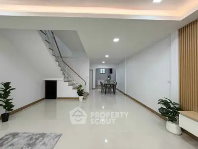 Spacious modern living room with sleek staircase and dining area, perfect for contemporary living.