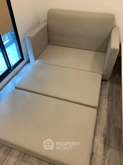 Compact beige sofa bed in modern apartment with wooden flooring