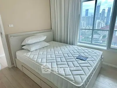 Modern bedroom with city view, featuring a comfortable bed and large window in a high-rise apartment.