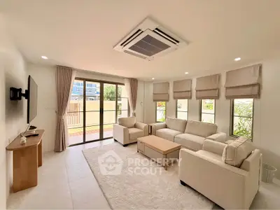 Spacious living room with modern furniture and large windows opening to a balcony.