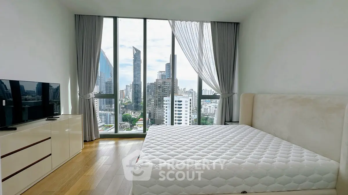 Modern bedroom with city view, large windows, and sleek furnishings in a high-rise apartment.