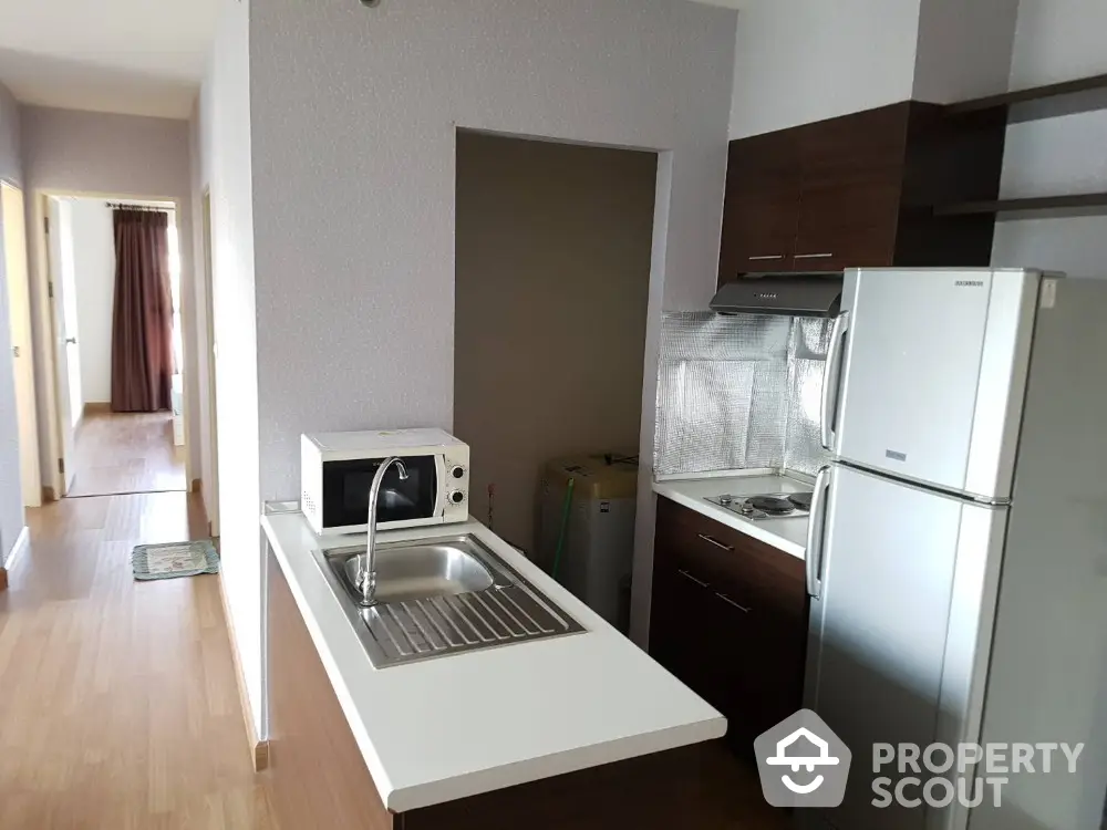 Modern kitchen with sleek appliances and wooden cabinetry in a cozy apartment setting.