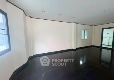 Spacious empty room with glossy black tile flooring and large windows