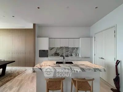 Luxurious modern kitchen with marble island and sleek cabinetry in upscale apartment.
