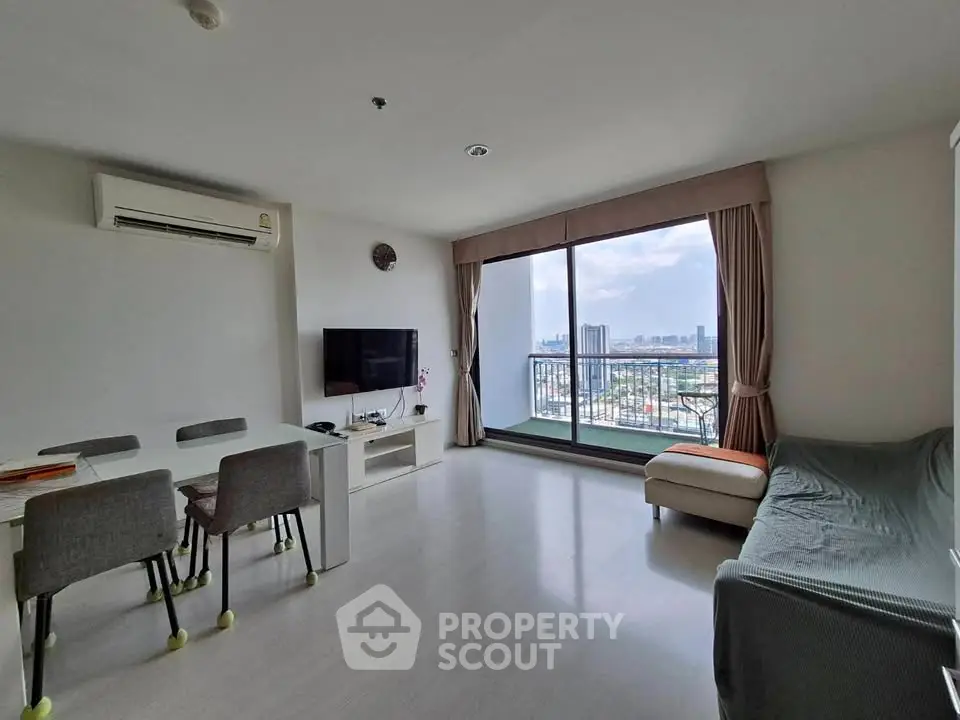Spacious living room with large window offering stunning city views, modern furniture, and natural light.