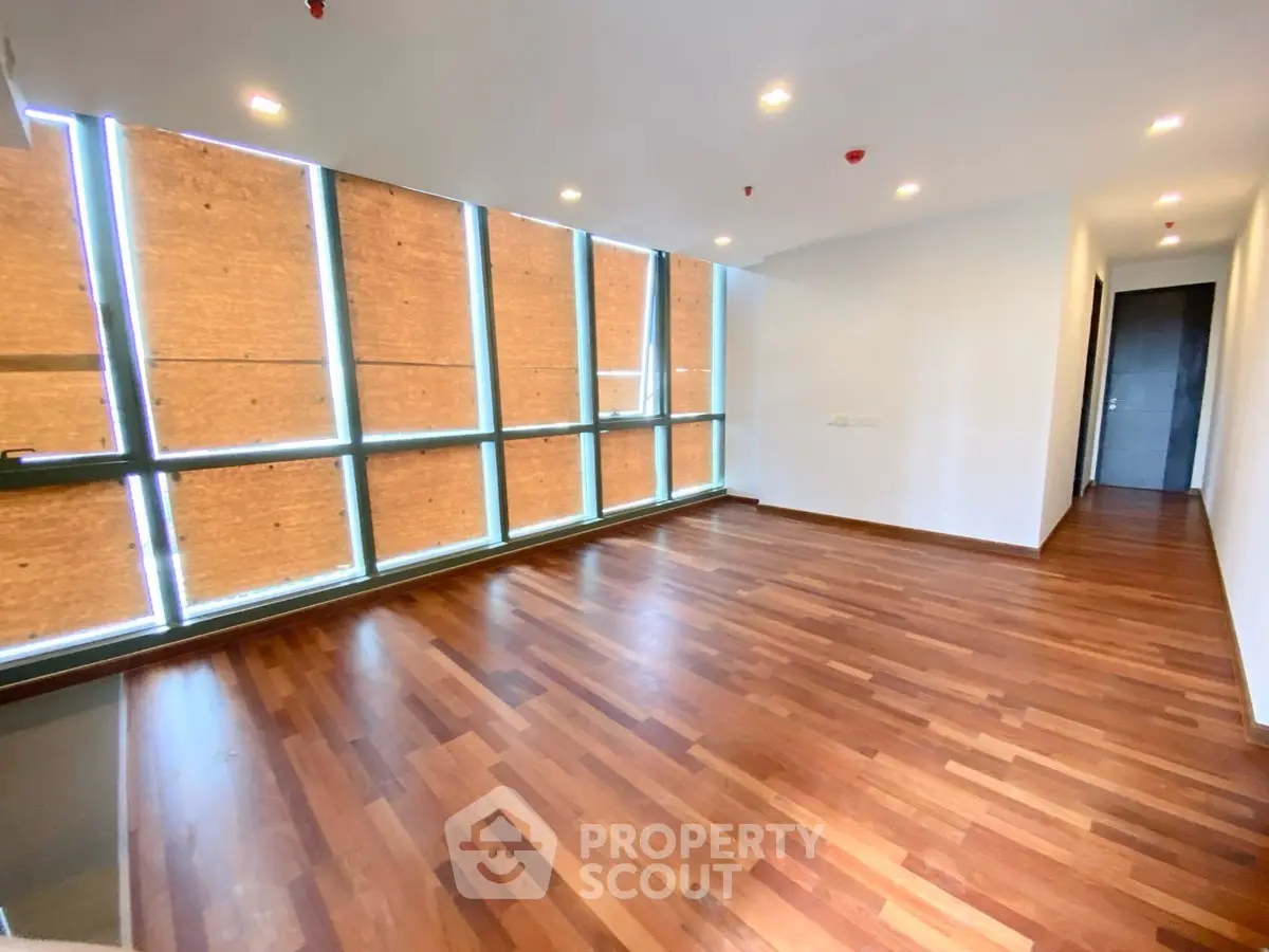 Spacious empty living room with wooden flooring and large windows