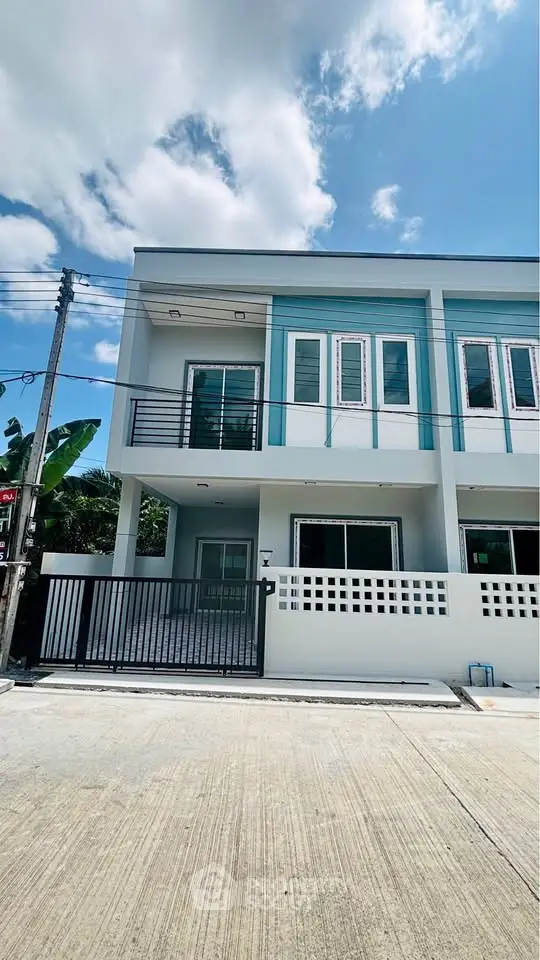 Modern two-story townhouse with sleek design and gated entrance under a clear blue sky.