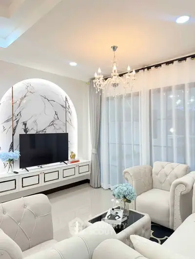 Luxurious living room with elegant chandelier and plush seating, featuring a modern TV setup and marble accents.