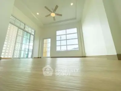 Spacious and bright living room with large windows and ceiling fan, perfect for modern living.