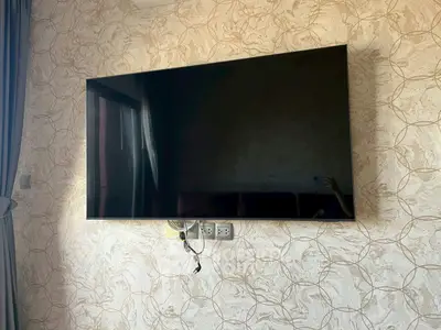 Modern living room with large wall-mounted TV and elegant wallpaper design.