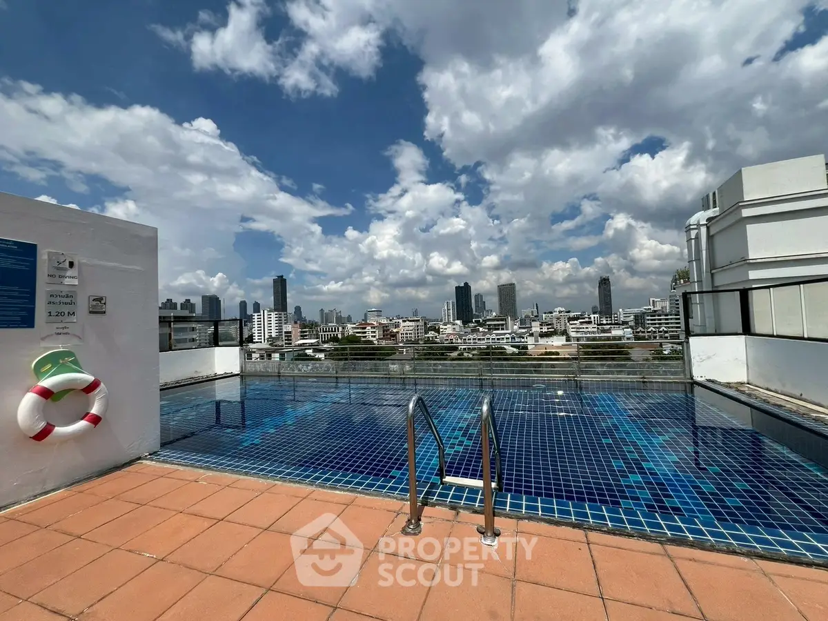 Stunning rooftop pool with panoramic city skyline views under a vibrant blue sky.