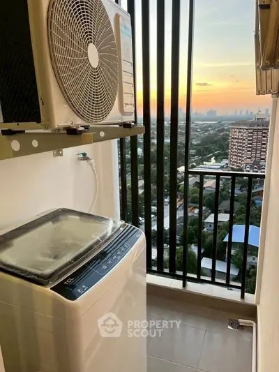Compact balcony with washing machine and stunning city view at sunset.