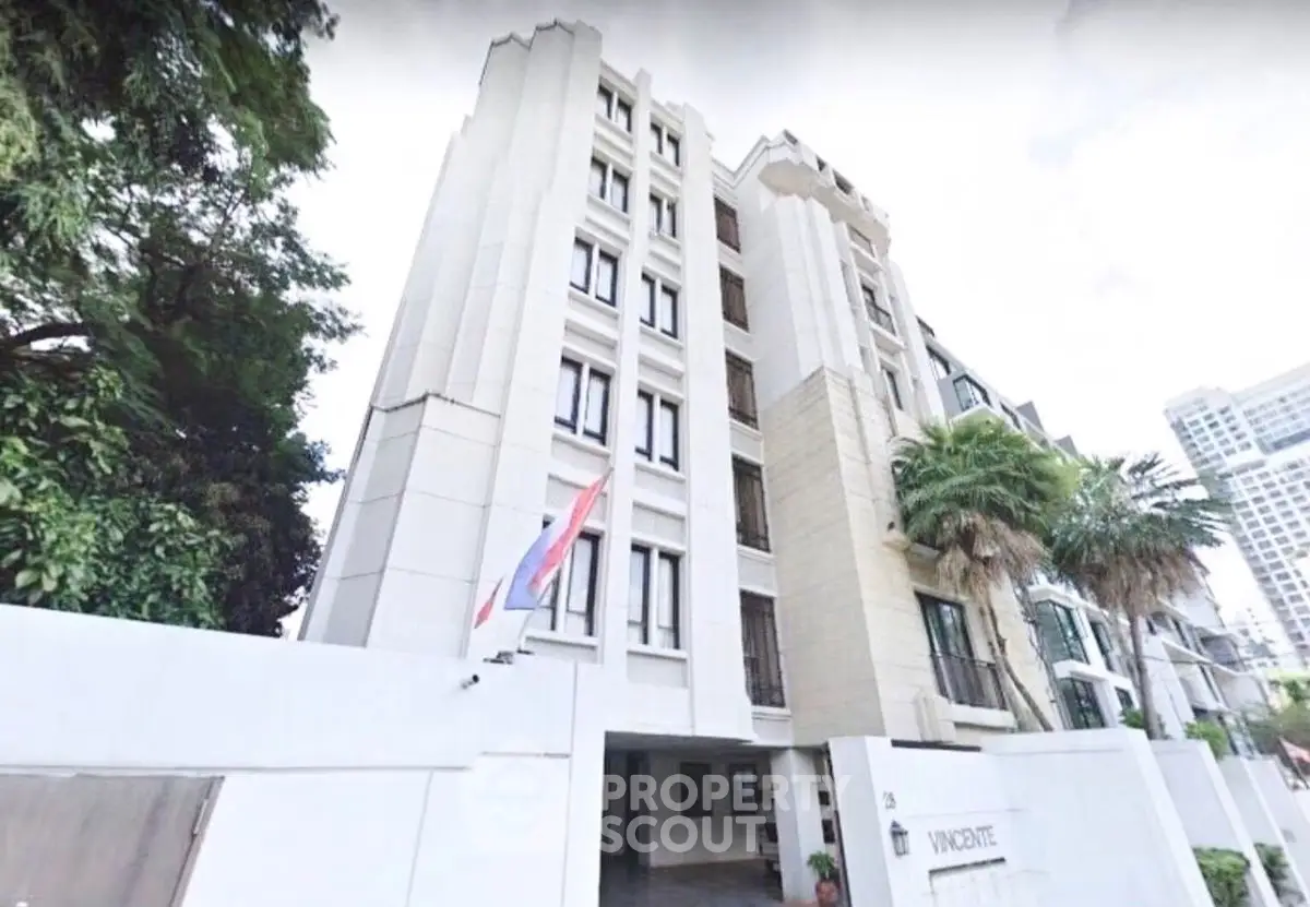 Elegant multi-story residential building with lush greenery and modern architecture.