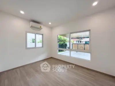 Spacious empty room with large windows and wooden flooring, perfect for customization.