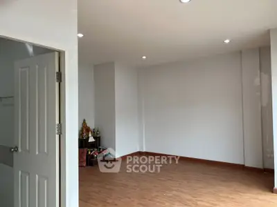 Spacious empty room with wooden flooring and recessed lighting, ideal for customization.