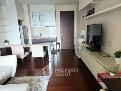 Modern living room with open kitchen, sleek furniture, and hardwood floors in a stylish apartment.
