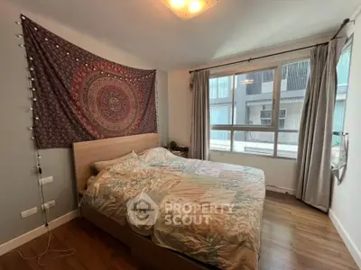 Cozy bedroom with large window and stylish tapestry, perfect for relaxation.