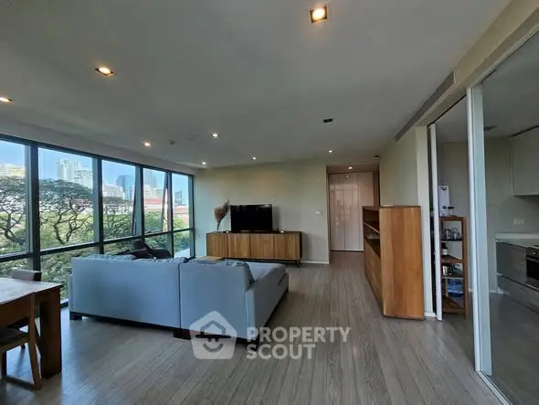 Spacious living room with large windows offering stunning city views and modern furnishings.