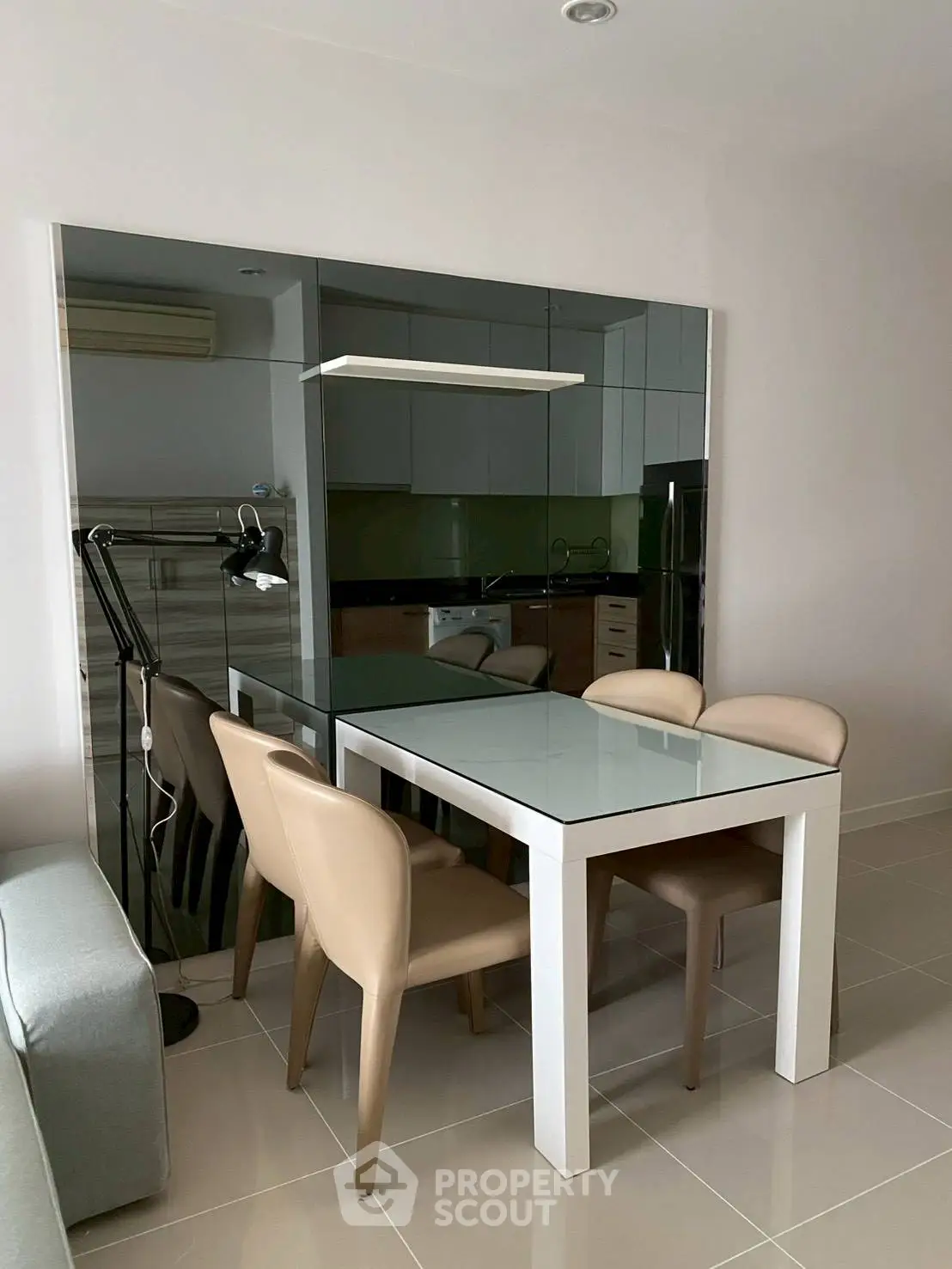 Modern dining area with sleek glass table and beige chairs in stylish apartment.