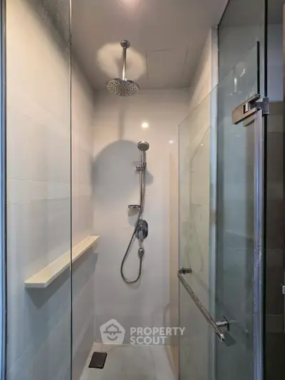 Modern shower with glass door and rainfall showerhead in sleek bathroom.