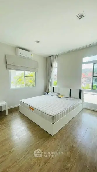Spacious bedroom with large windows and natural light, featuring modern minimalist design and wooden flooring.