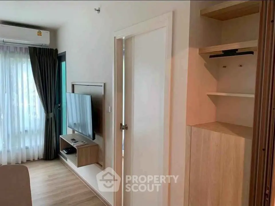 Modern living room with wall-mounted TV and stylish shelving in a cozy apartment.