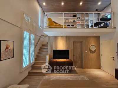 Modern loft-style living room with mezzanine, stylish decor, and natural light.