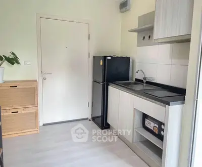 Modern compact kitchen with sleek cabinetry and black appliances in a cozy apartment.