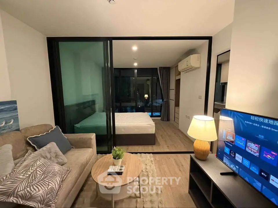 Modern studio apartment with glass partition, cozy living area, and stylish decor.