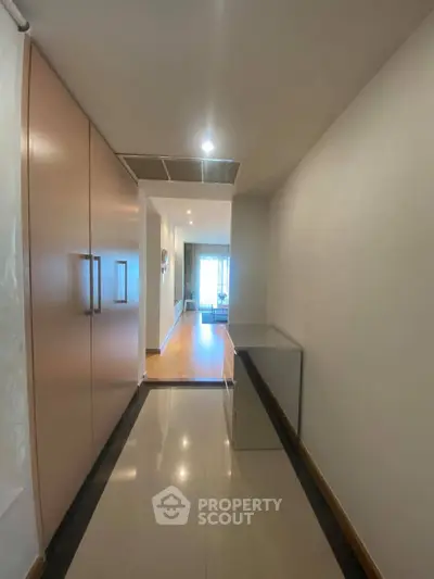 Spacious hallway leading to a bright living room with modern decor and large windows.