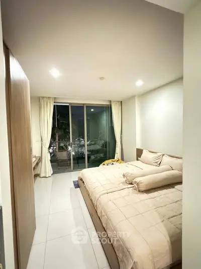 Cozy bedroom with large bed and balcony access in modern apartment