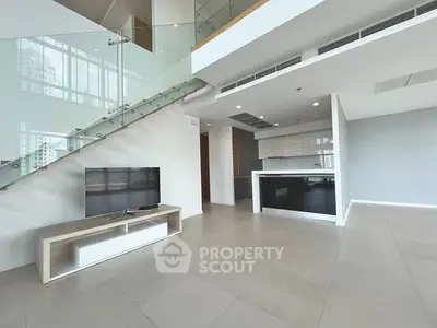 Spacious modern living room with open kitchen and sleek staircase in luxury apartment