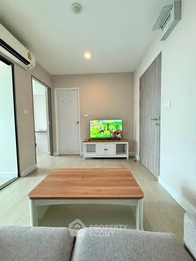 Modern living room with sleek furniture and TV, featuring a cozy ambiance and neutral tones.