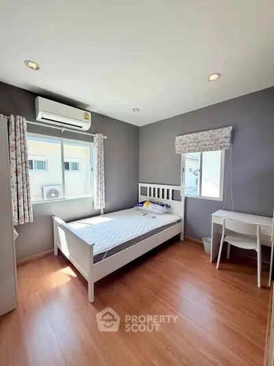 Bright and cozy bedroom with wooden flooring and ample natural light.