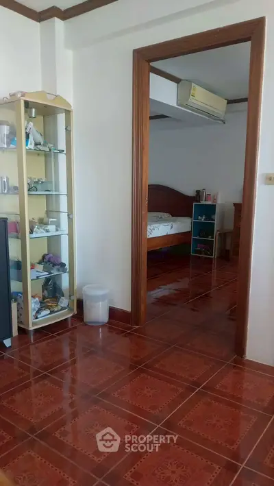 Spacious bedroom with wooden flooring and glass display cabinet, perfect for cozy living.