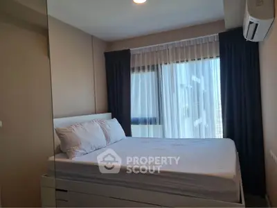 Cozy bedroom with large window and modern air conditioning unit, perfect for relaxation.
