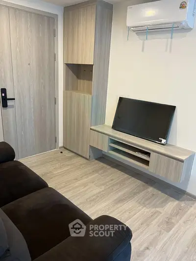 Modern living room with sleek TV unit and air conditioning, featuring stylish wood flooring and cozy seating.