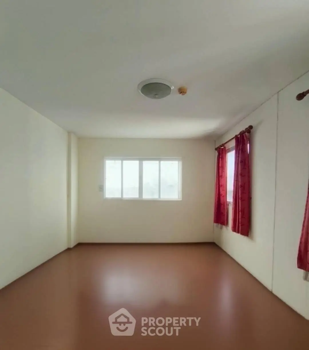 Spacious empty room with large window and red curtains, perfect for customization.