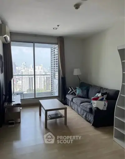 Modern living room with city view, featuring cozy sofa and sleek decor in high-rise apartment.