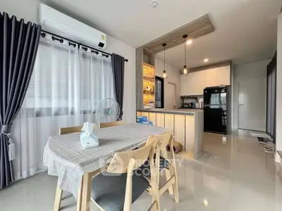 Modern dining area with open kitchen, featuring stylish lighting and sleek furniture.