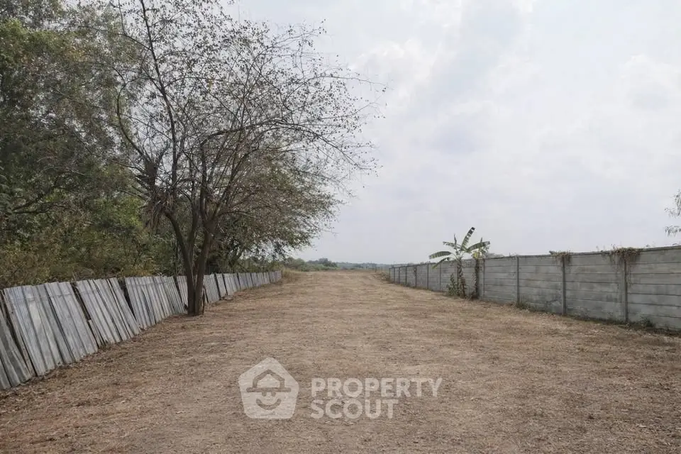 Expansive plot of land with potential for development, featuring a clear pathway and natural surroundings.