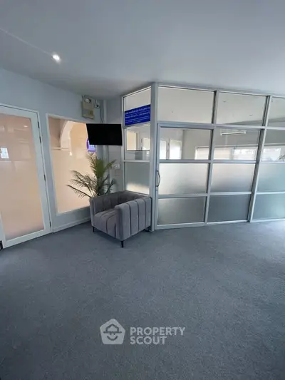 Modern office space with frosted glass partitions and a cozy armchair, ideal for professional settings.