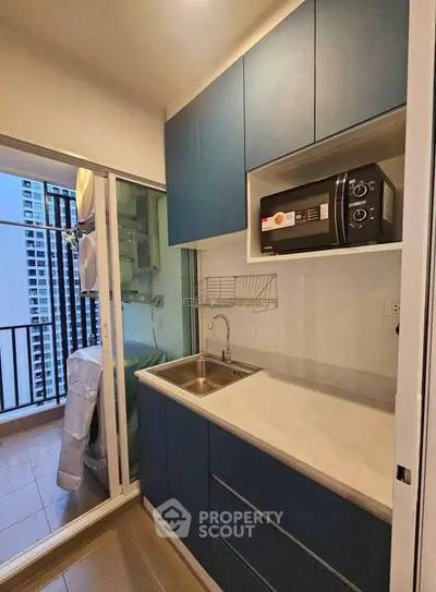 Modern compact kitchen with blue cabinets and balcony view