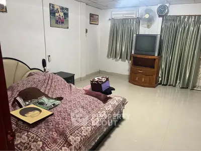 Cozy living room with vintage TV and air conditioning, featuring elegant curtains and a comfortable sofa.